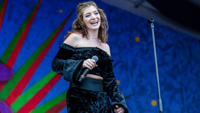 Lorde performing in a blue velour outfit.