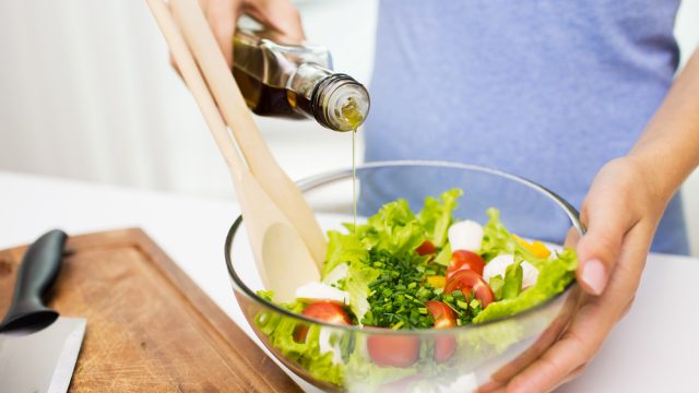Woman pouring olive oil into a salad