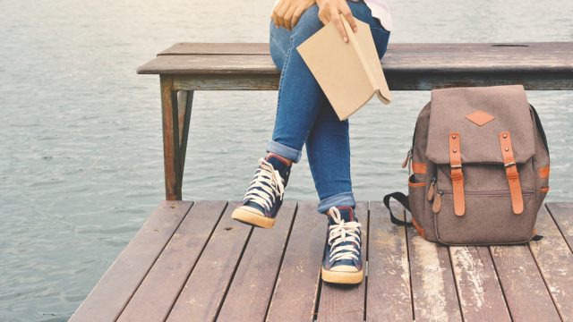 girl sitting on a bench with a book