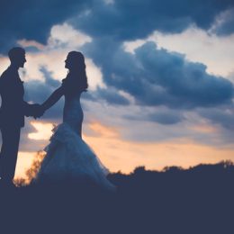 Bride and groom stand under a sunset