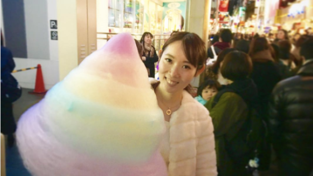 A woman holds a giant rainbow cotton candy at Totti Candy Factory in Tokyo