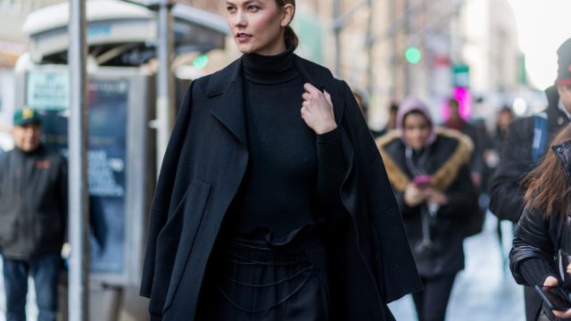 Model Karlie Kloss wearing a black coat, black turtleneck, black jogger pants outside Calvin Klein