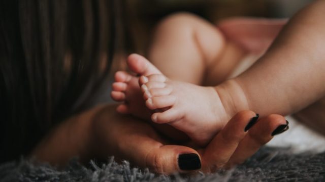 woman cradles newborn baby's feet