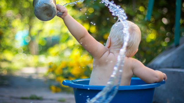 baby throwing water over his shoulder