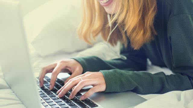 Woman in bed on computer having fun.