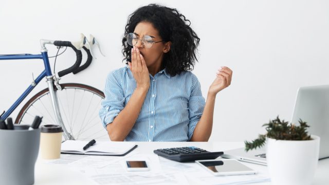 Woman yawming at her desk.