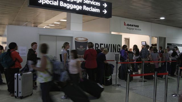 Passengers line up to retrieve checked in baggage from Qantas Airlines