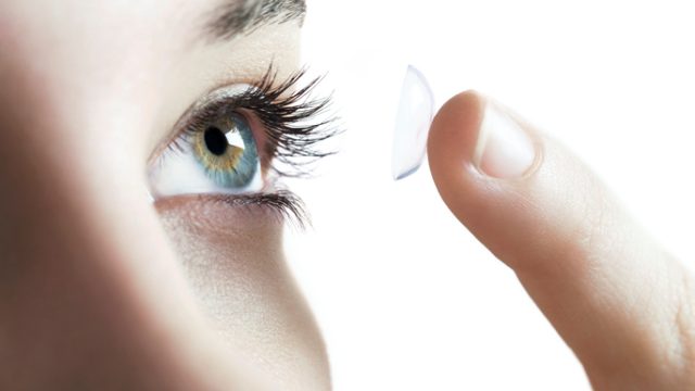 Contact lens use. Woman putting in a contact lens.