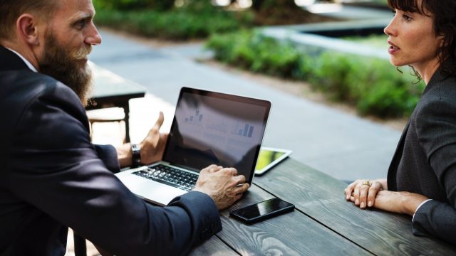 man with laptop talks with woman