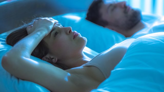 Woman lying in bed not being able to sleep.