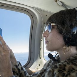 A woman takes a photo with her cell phone during a private flight on a small airplane.