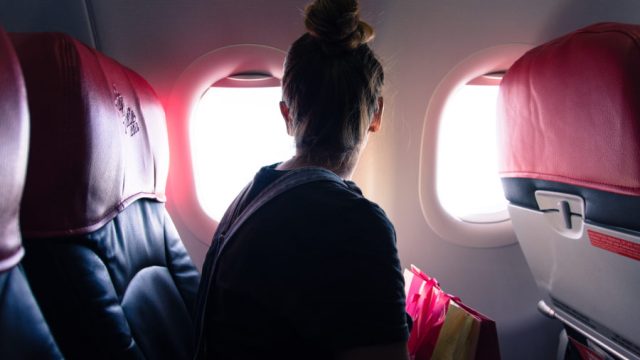 Woman Looking Through Window While Traveling In Airplane