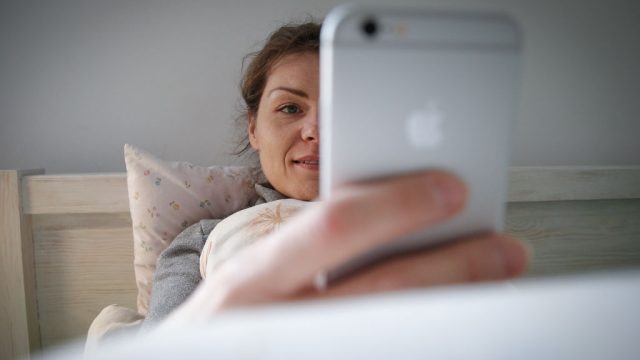 A woman looks at her phone in bed