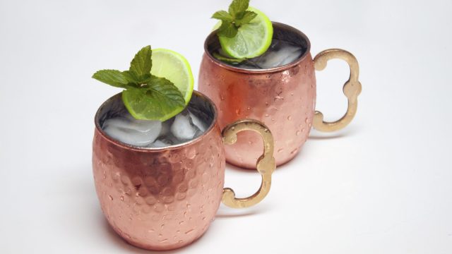 Two Moscow mule drinks in brightly colored copper mugs