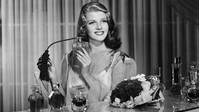 American film actress, dancer and singer Rita Hayworth (1918 - 1987) sprays herself with perfume at a dressing table.