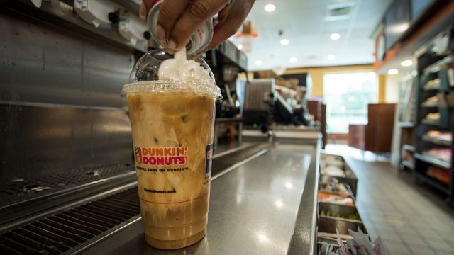 An employee tops a coffee drink with whipped cream at a Dunkin' Donuts Inc. location in Ramsey, New Jersey, U.S., on Thursday, May 5, 2016. Dunkin' Brands Group Inc., a leading franchiser in the quick service restaurants (QSR) sector, operates in almost 60 countries around the world with more than 11,300 Dunkin' Donuts restaurants and 7,500 Baskin-Robbins locations. Photographer: Ron Antonelli/Bloomberg via Getty Images
