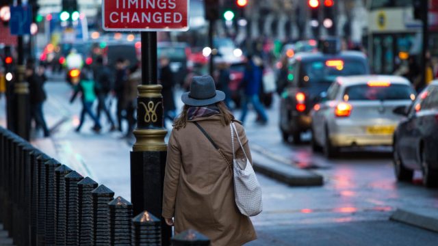 woman-wearing-trench-coat-hat-walking-down-busy-street