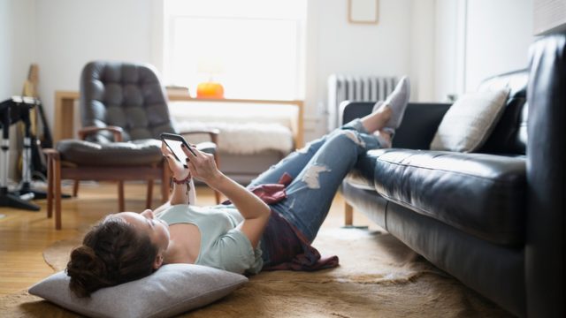 Woman laying with feet up texting cell phone
