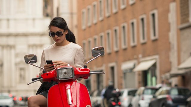 Young woman waiting by moped, Piazza del Popolo, Rome, Italy