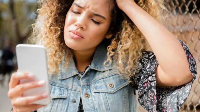 Unhappy Mixed Race woman texting on cell phone