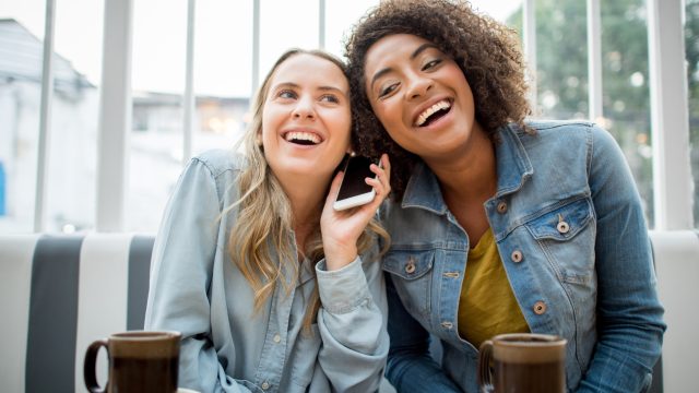 Friends at a cafe listening to the voice mail