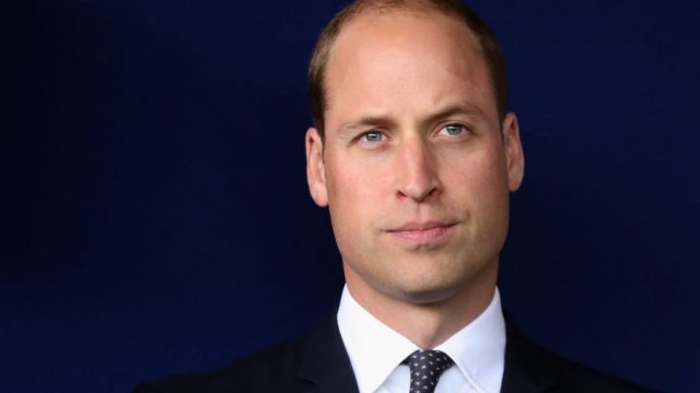 Prince William stands against a dark background