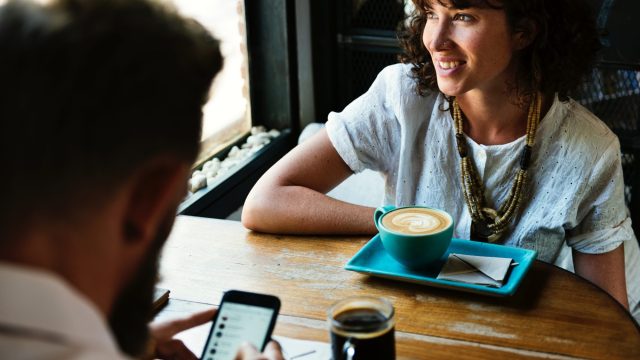 woman-with-cup-of-coffee-sits-across-from-date