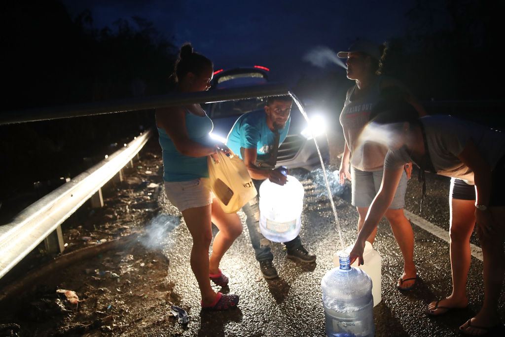 UTUADO, PUERTO RICO - OCTOBER 06:  People collect spring water in containers from a pipe along side a highway since they have no running water in their home after Hurricane Maria passed through on October 6, 2017 in Utuado, Puerto Rico.  Puerto Rico experienced widespread damage including most of the electrical, gas and water grid as well as agriculture after Hurricane Maria, a category 4 hurricane, passed through.  (Photo by Joe Raedle/Getty Images)
