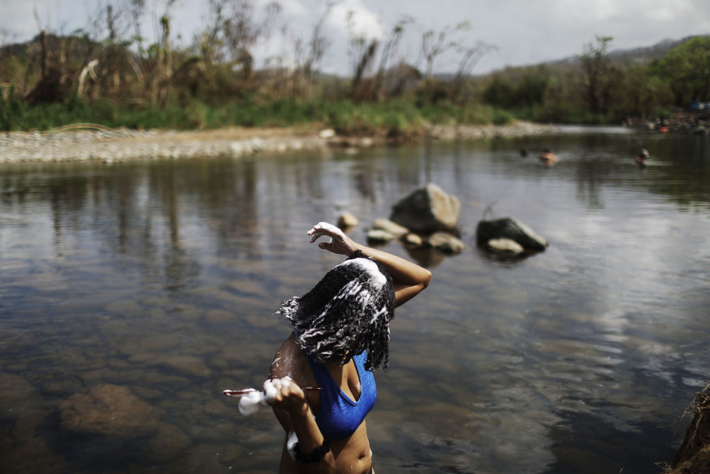 PALMER, PUERTO RICO - OCTOBER 08:  A woman washes her hair in the Espiritu Santo river, along hurricane-damaged forest, more than two weeks after Hurricane Maria hit the island, on October 8, 2017 in Palmer, Puerto Rico. Only 11.7 percent of Puerto Rico's electricity has been restored and some residents are going to the river to cool off, wash clothes, gather water or bathe. The area borders the El Yunque National Forest, the United States' only tropical rainforest, which was heavily damaged by the hurricane. Puerto Rico experienced widespread damage including most of the electrical, gas and water grid as well as agriculture after Hurricane Maria, a category 4 hurricane, swept through.  (Photo by Mario Tama/Getty Images)