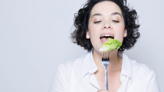 Woman eating lettuce off fork