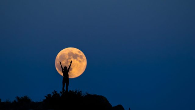 Image of woman in front of full moon