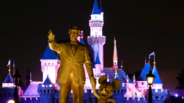 A statue of Walt Disney and Mickey Mouse in front of the Sleeping Beauty Castle at Disneyland Park in Anaheim, California