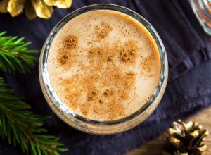 Eggnog with cinnamon in glass close up with Christmas decor - homemade traditional festive drink for Christmas time