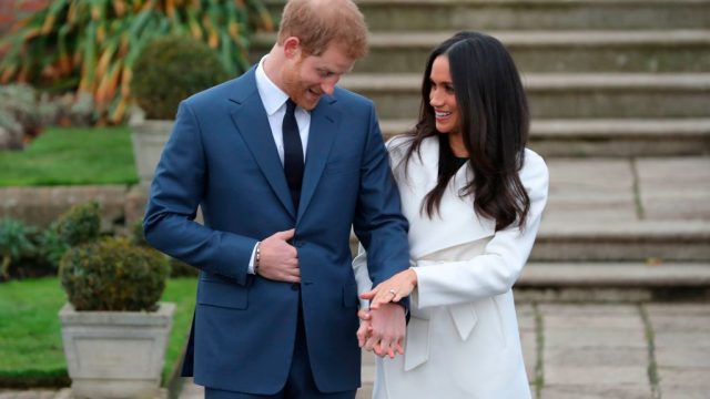 Britain's Prince Harry stands with his fiancée US actress Meghan Markle as she shows off her engagement ring whilst they pose for a photograph in the Sunken Garden at Kensington Palace in west London on November 27, 2017, following the announcement of their engagement.