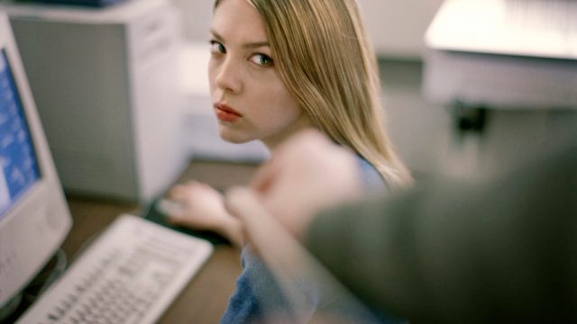 woman at desk giving dirty look to prankster.