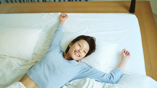 Young woman lying on bed, smiling, elevated view