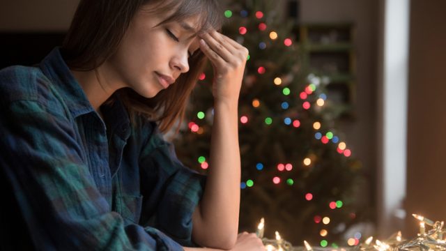 Woman sad in front of Christmas tree