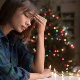 Woman sad in front of Christmas tree