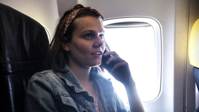 Woman using mobile phone inside airplane