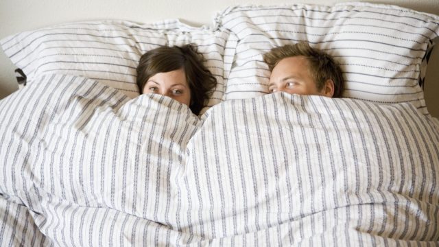 Photo of Couple Cuddling Under the Blankets