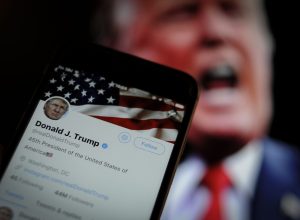Photo of Twitter App with Donald Trump in the Background