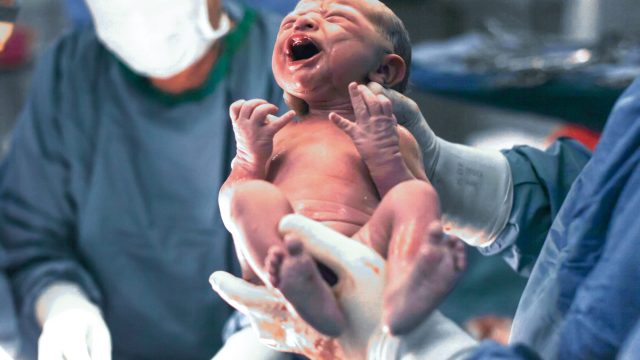 Photo of Doctors Holding Newborn Baby