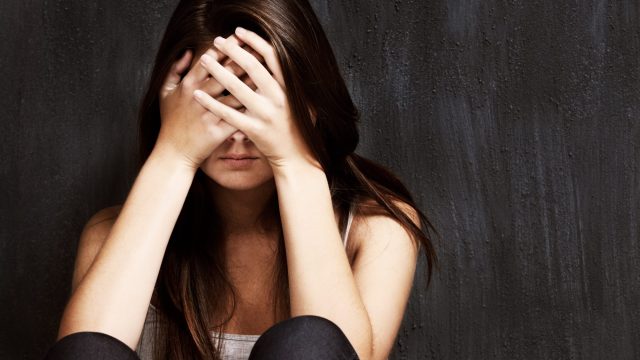 Photo of Sad Young Woman Holding Her Head in Her Hands