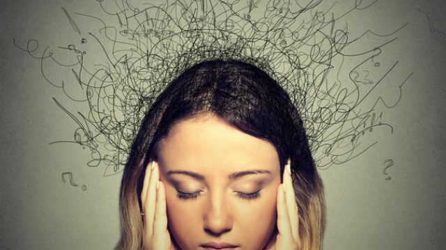 Young woman with stressed expression and question marks around her head