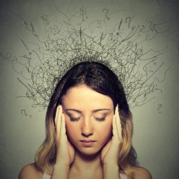 Young woman with stressed expression and question marks around her head