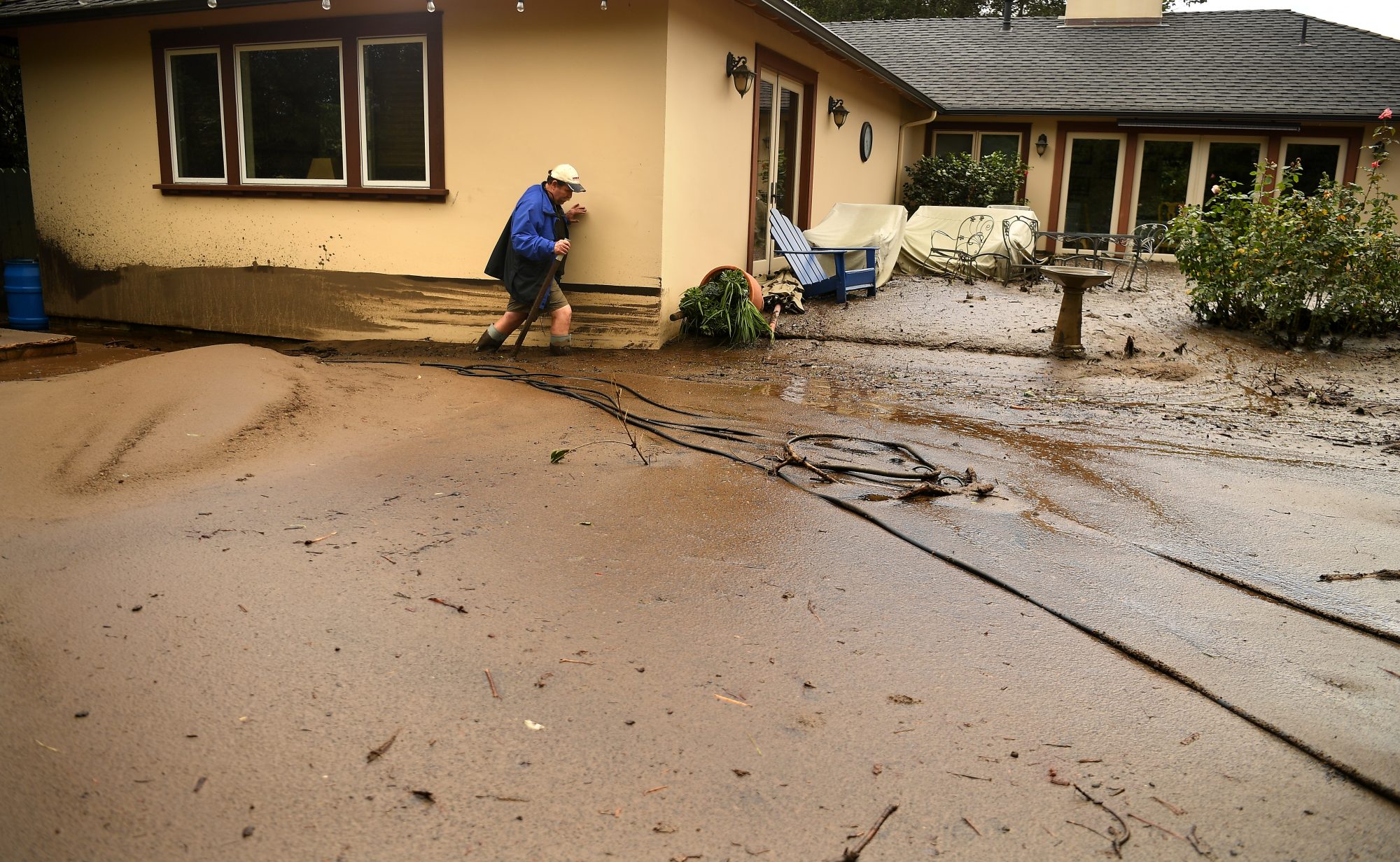 MONTECITO, CA - JANUARY 09: Mark Olson tries to access his house as he climbs through mud in his back yard along Olive Mill Road in Montecito after a major storm hit the burn area Tuesday January 9, 2018 in Montecito, California.