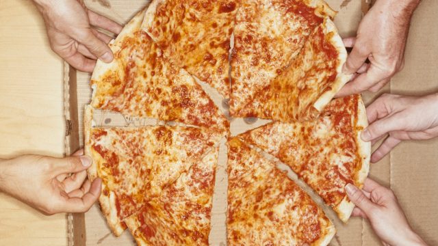Hands Holding Pizza Slices