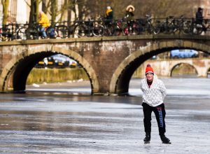 Photo of a Man Ice Skating on a Frozen Canal in Amsterdam