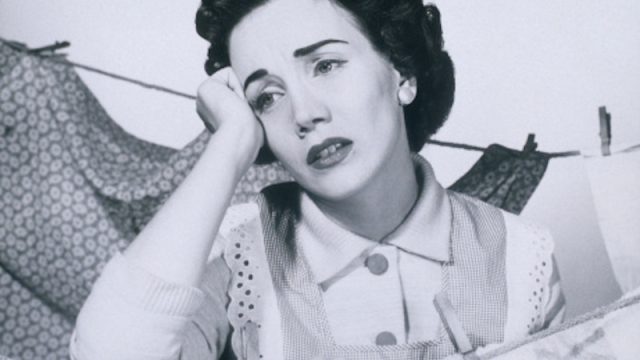 Anguished 1950s woman hanging clothes