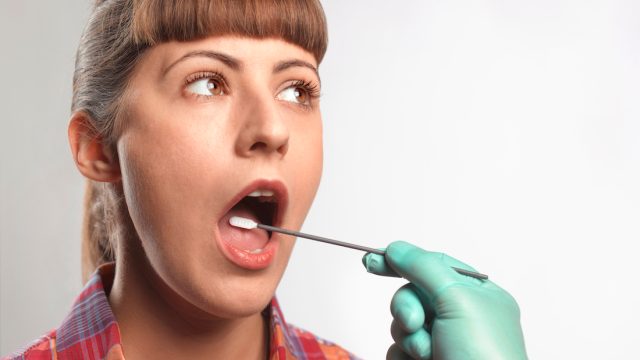 Person putting DNA test swab into woman's mouth